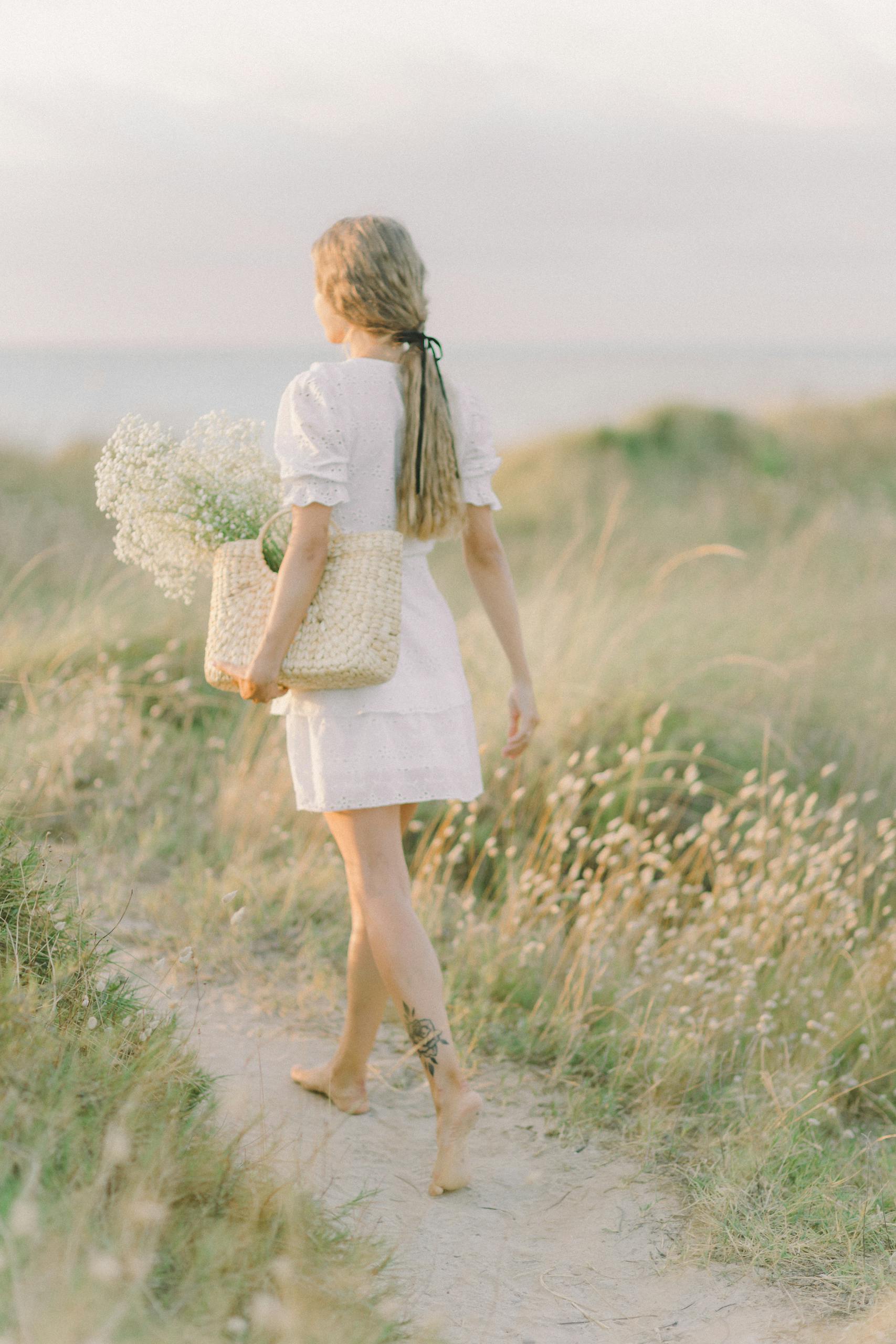 Woman in White Dress Holding a Woven Bag